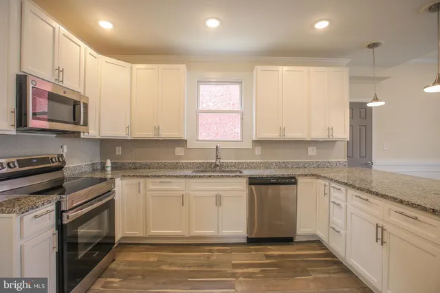 a kitchen with stainless steel appliances granite countertop a stove a sink and a microwave