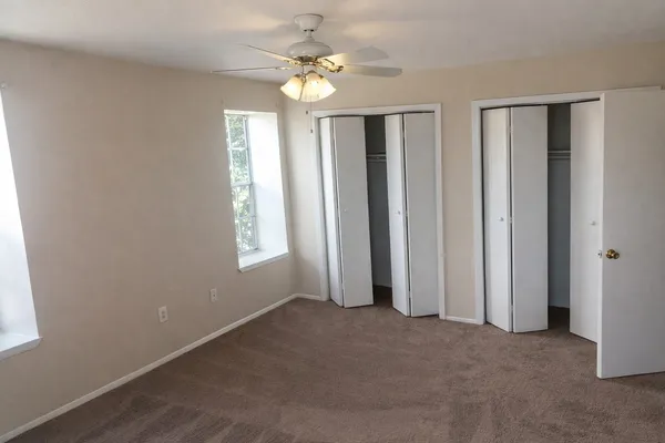 an empty room with windows and fan