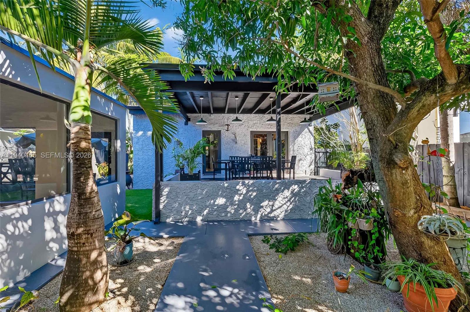 452 Southwest 21st Road Miami, FL 33129 - Photo 40 of 51 a view of a patio with table and chairs potted plants and large tree