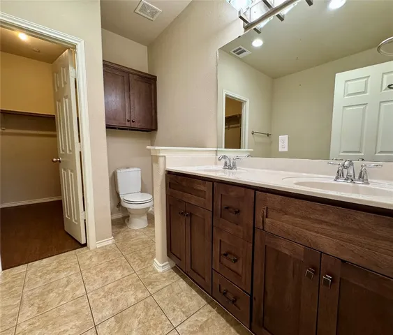 a spacious bathroom with a double vanity sink a toilet and a mirror