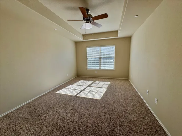 an empty room with windows and ceiling fan