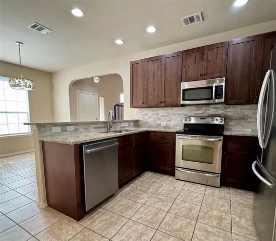 a kitchen with sink a microwave and cabinets