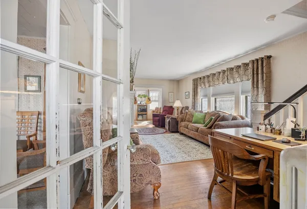 a living room with furniture a large window and wooden floor
