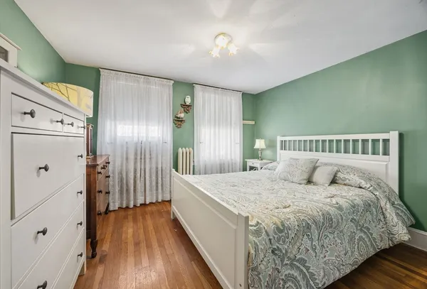 a spacious bedroom with a bed and wooden floor