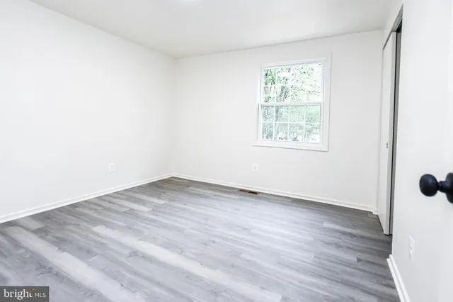 an empty room with wooden floor and window