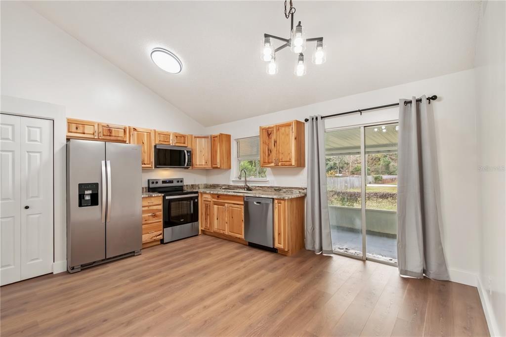 7670 Southwest 80th Place Ocala, FL 34476 - Photo 12 of 44 a kitchen with stainless steel appliances granite countertop a refrigerator a stove top oven a sink and dishwasher with wooden floor