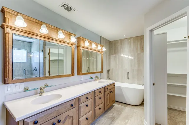 a bathroom with a double vanity sink large mirror and a bathtub