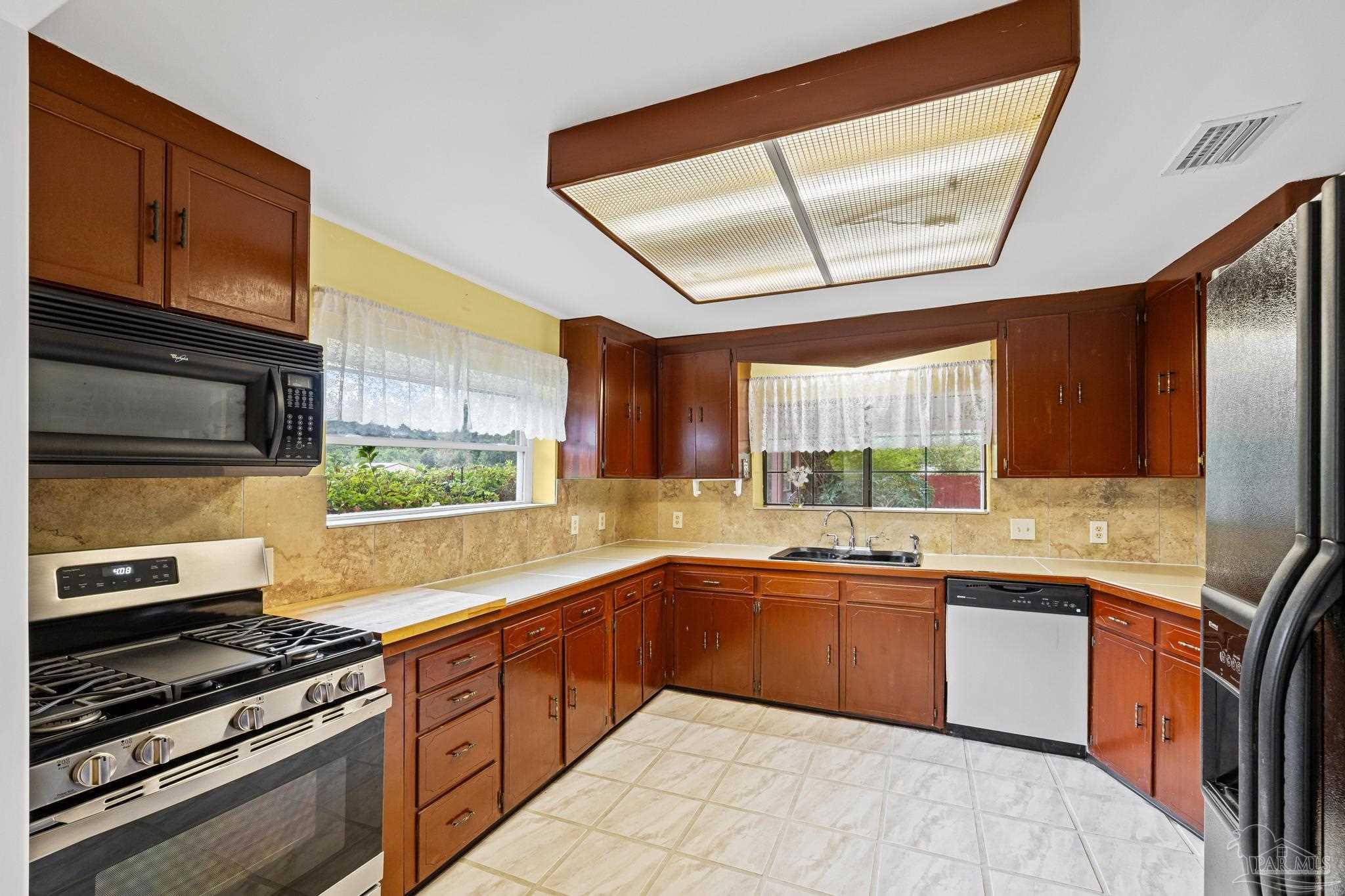 3811 Wilkes Street Pace, FL 32571 - Photo 16 of 59 a kitchen with stainless steel appliances a stove sink and microwave