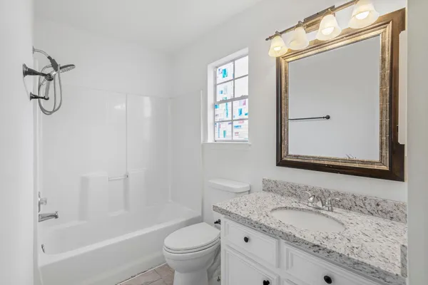 a bathroom with a granite countertop sink toilet and a mirror