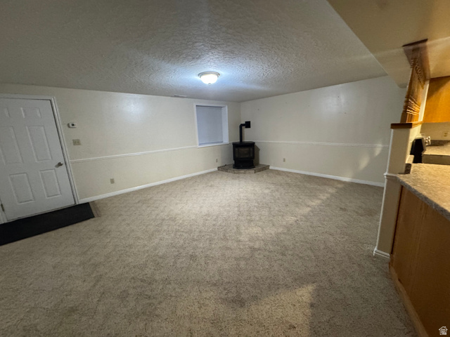 655 North 8th East Preston, ID 83263 - Photo 14 of 32 Finished basement with a textured ceiling, a wood stove, and light colored carpet