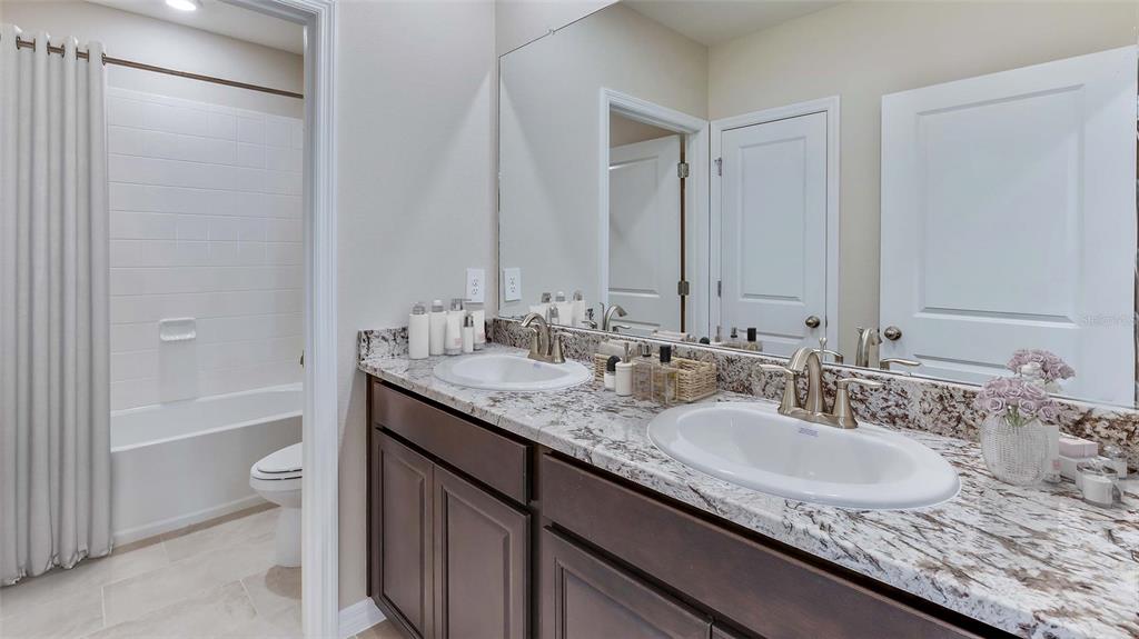11932 Kingsley Trail Parrish, FL 34219 - Photo 16 of 26 a bathroom with a granite countertop sink a toilet and shower