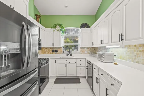 a kitchen with white cabinets and appliances