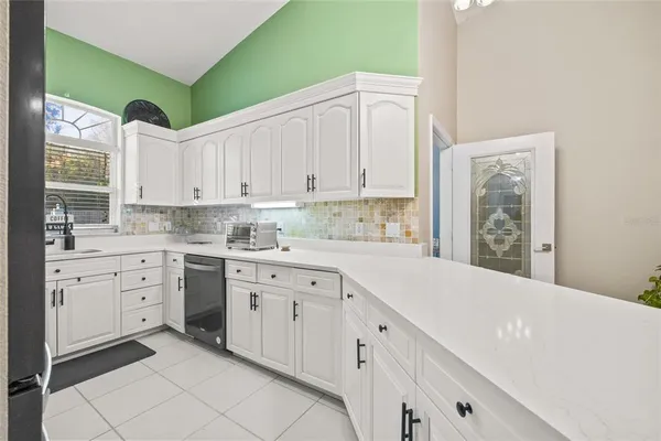 a kitchen with white cabinets and chandelier