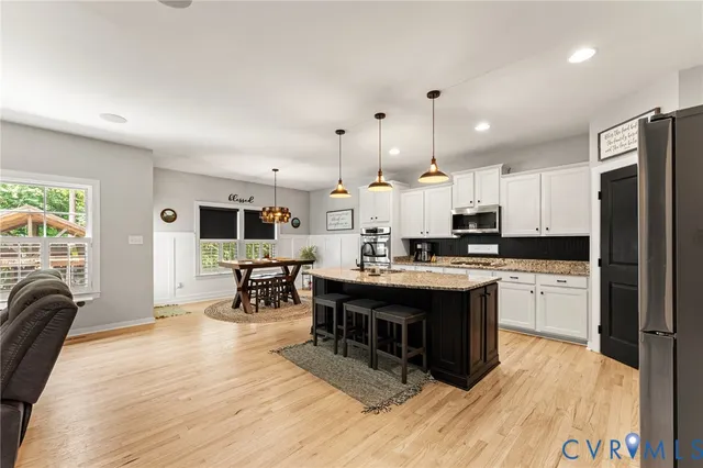 a kitchen with stainless steel appliances granite countertop a refrigerator a stove top oven a sink dishwasher and white cabinets with wooden floor