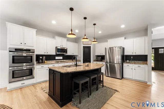 a kitchen with stainless steel appliances kitchen island granite countertop a table chairs stove and refrigerator