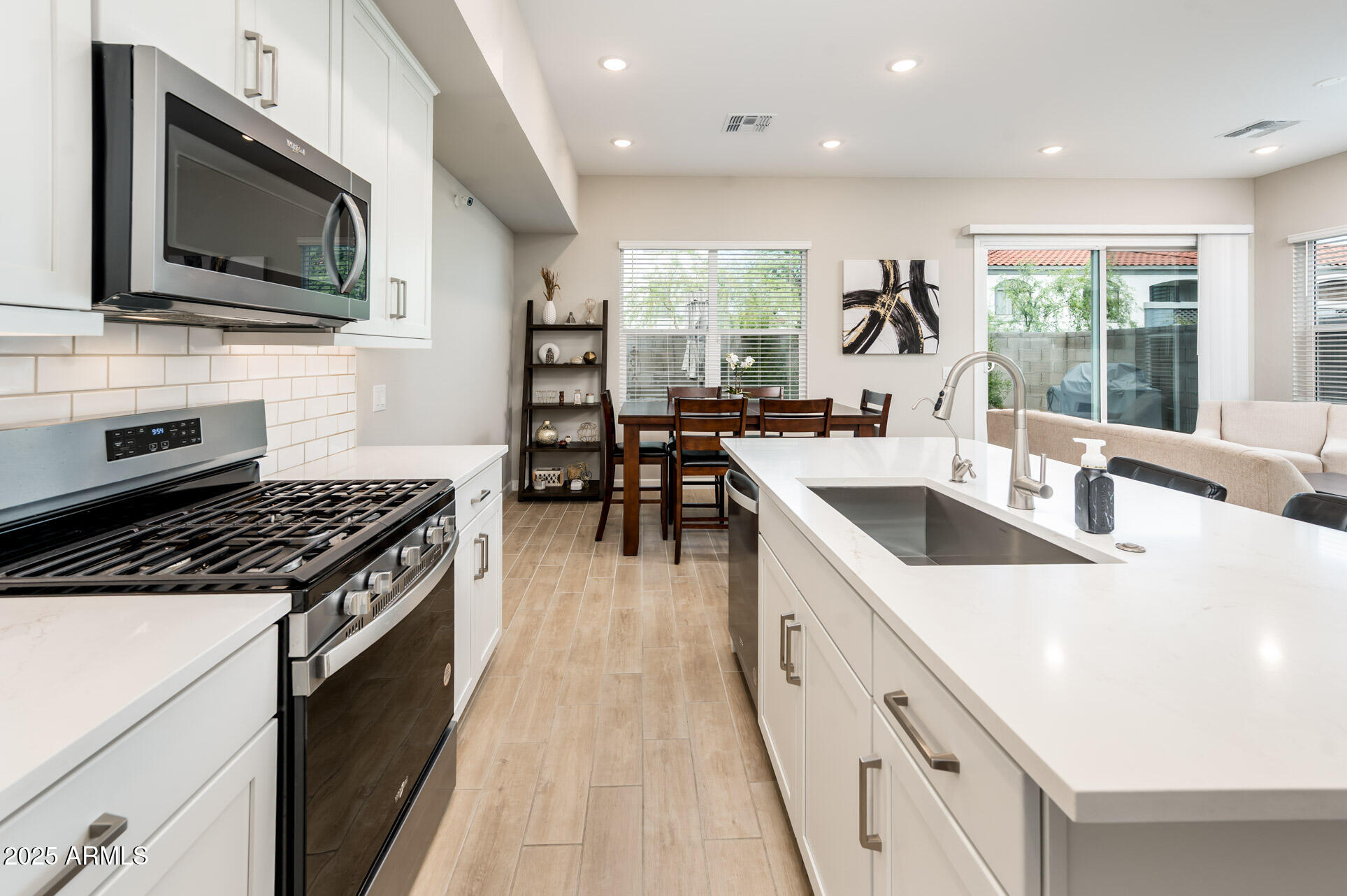 17146 North 50th Street Scottsdale, AZ 85254 - Photo 22 of 51 a open kitchen with stainless steel appliances granite countertop a stove top oven a sink dishwasher a dining table and chairs with wooden floor