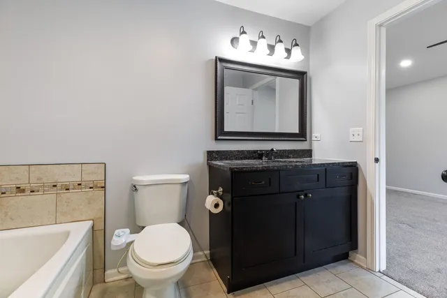 a bathroom with a toilet sink vanity and mirror