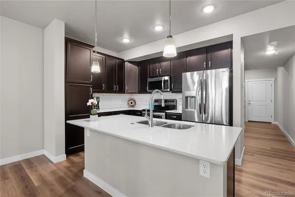 a kitchen with stainless steel appliances granite countertop a refrigerator a sink a stove and oven