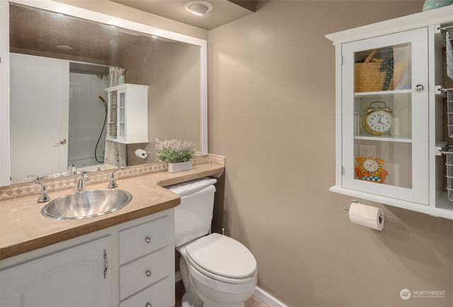 a bathroom with a granite countertop sink toilet and mirror