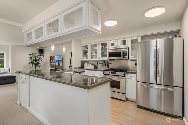 a kitchen with stainless steel appliances granite countertop a refrigerator a stove a sink and a microwave