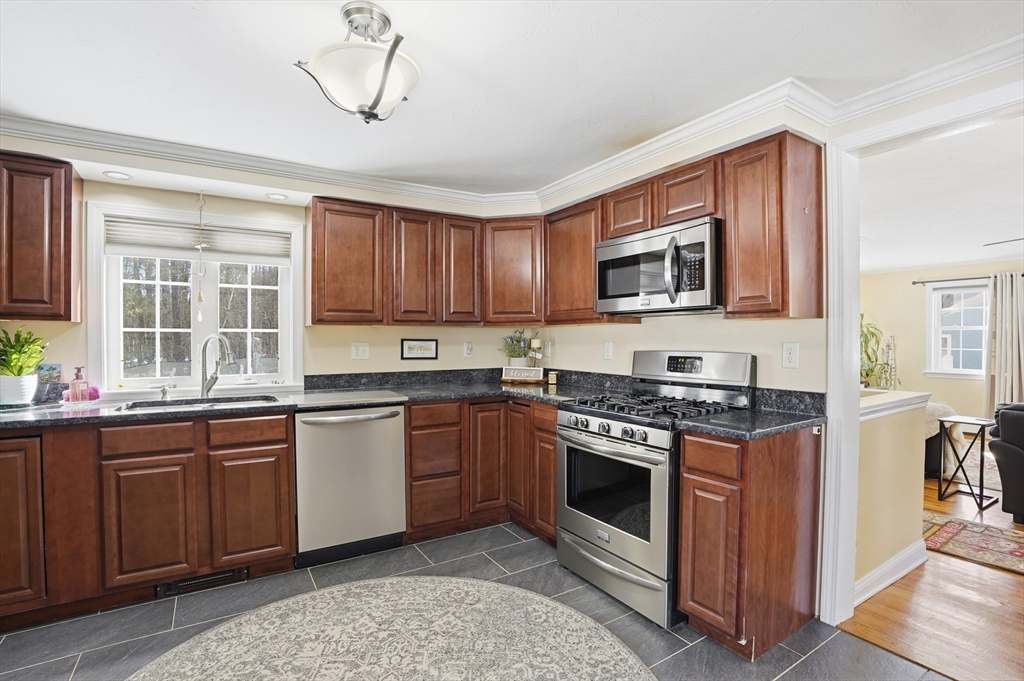 9 Kanehoe Court Townsend, MA 01474 - Photo 9 of 31 a kitchen with stainless steel appliances granite countertop a stove top oven a sink dishwasher a dining table and chairs with wooden floor