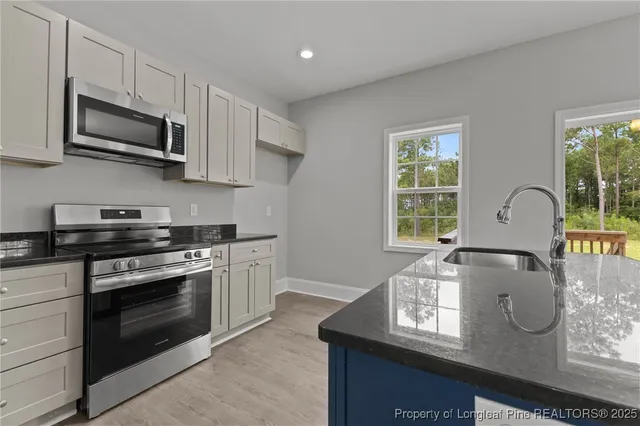 an empty room with wooden floor chandelier and windows