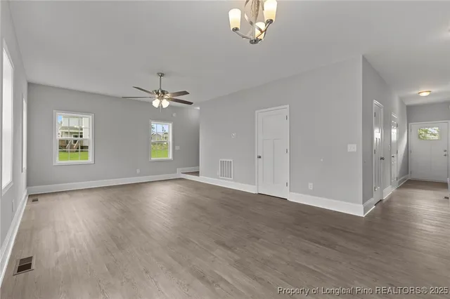 a view of an empty room with kitchen view and a ceiling fan
