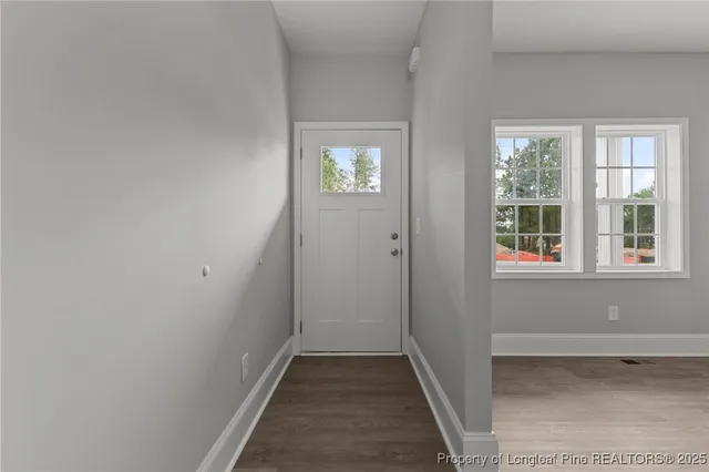 an empty room with wooden floor chandelier fan and windows