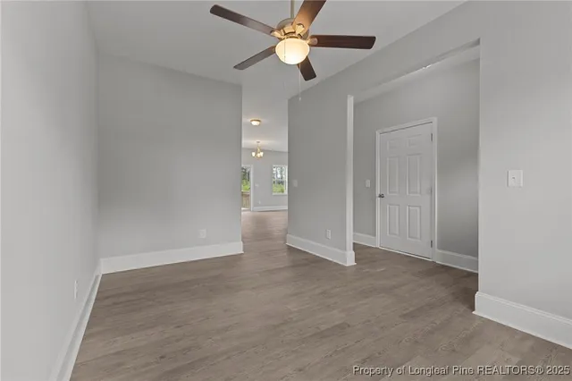 a view of an empty room with a window and wooden floor