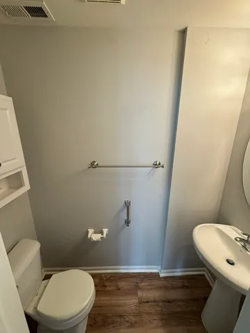 a white toilet sitting next to a bathroom sink and a mirror