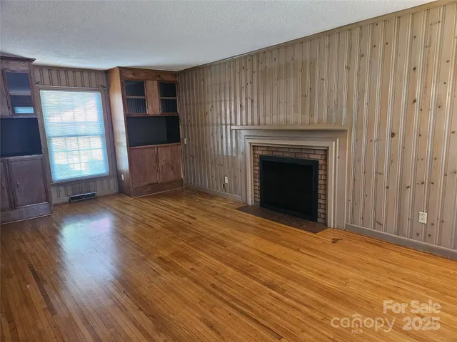 wooden floor fireplace and windows in an empty room