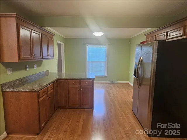 a kitchen with stainless steel appliances granite countertop a refrigerator a sink and wooden cabinets