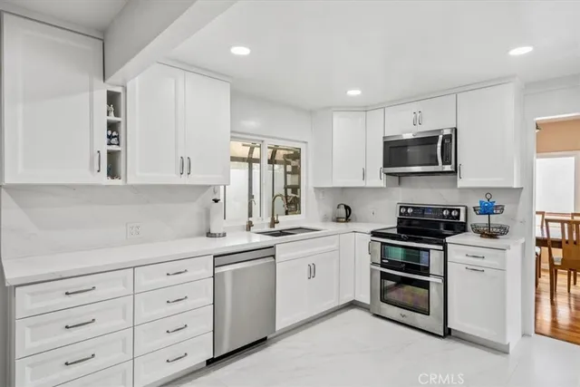 a kitchen with white cabinets and stainless steel appliances