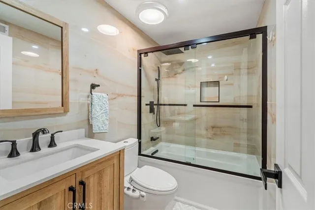 a bathroom with a granite countertop sink a toilet a mirror and shower