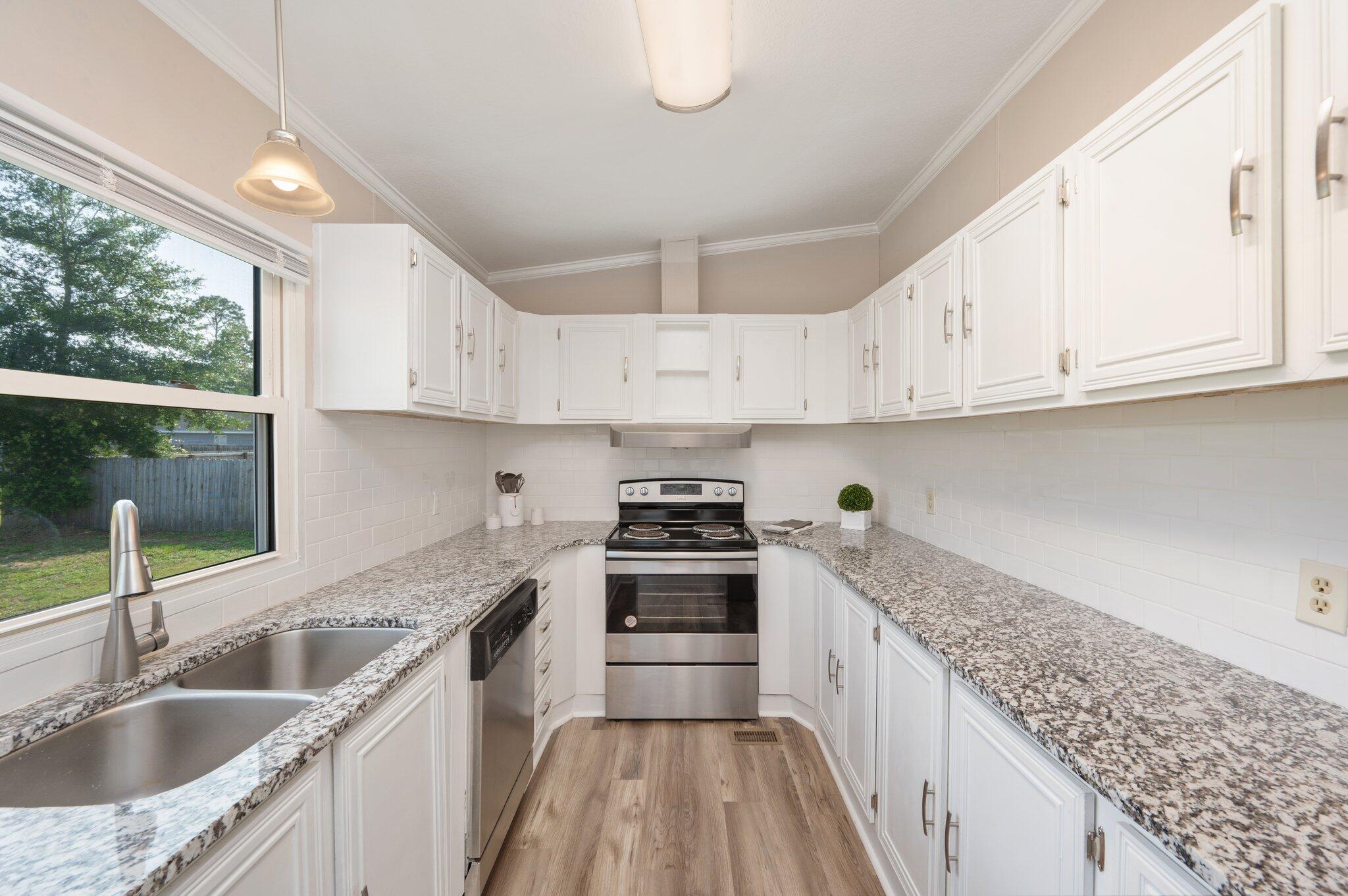 4625 Canary Way Crestview, FL 32539 - Photo 10 of 35 a kitchen with kitchen island granite countertop a sink stove and cabinets