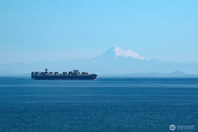a view of an empty room with wooden floor fireplace and a window