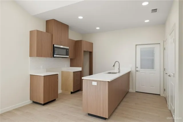 a kitchen with stainless steel appliances a microwave a sink and a refrigerator