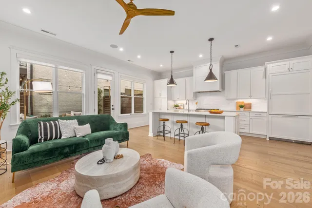 a living room with furniture kitchen view and a large window