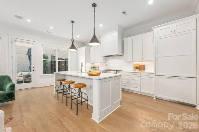 a kitchen with stainless steel appliances granite countertop a sink a stove a refrigerator and white cabinets with wooden floor