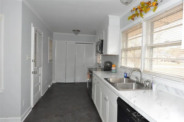 a kitchen with granite countertop a sink stove and cabinets