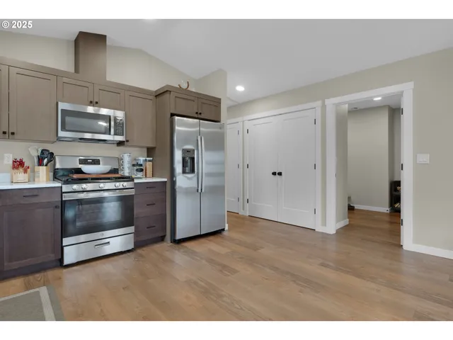 a kitchen with stainless steel appliances and wooden floor