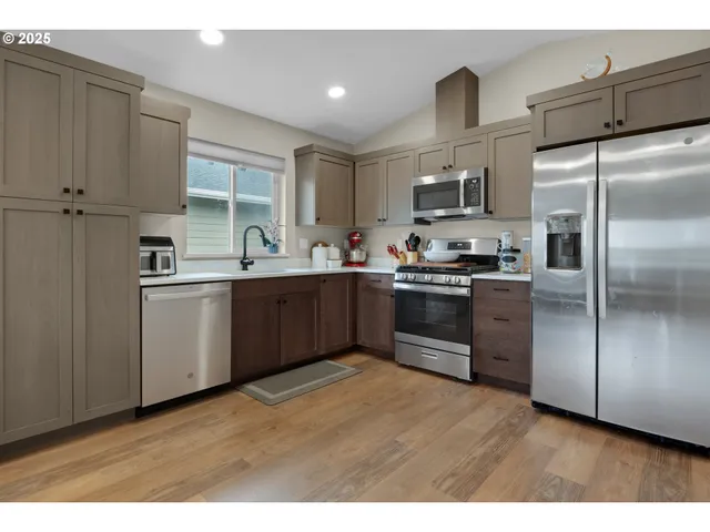 a kitchen with stainless steel appliances granite countertop a sink a stove a refrigerator with grey cabinets