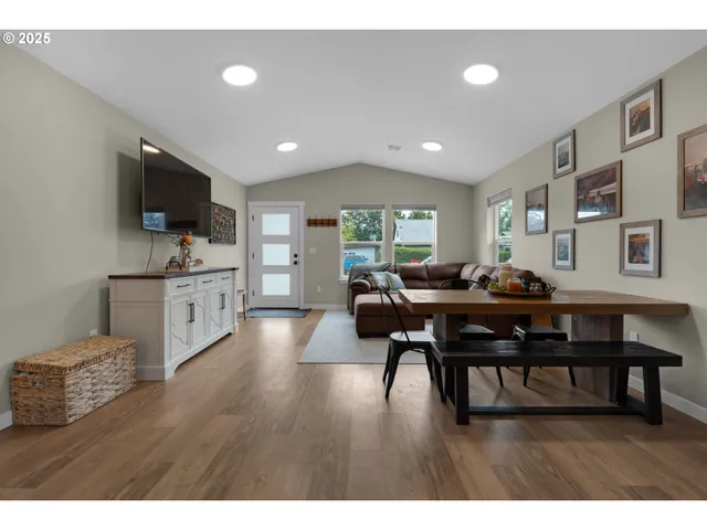 a living room with furniture a flat screen tv and a refrigerator