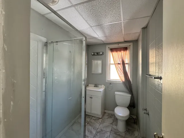 a bathroom with a granite countertop toilet a sink and shower