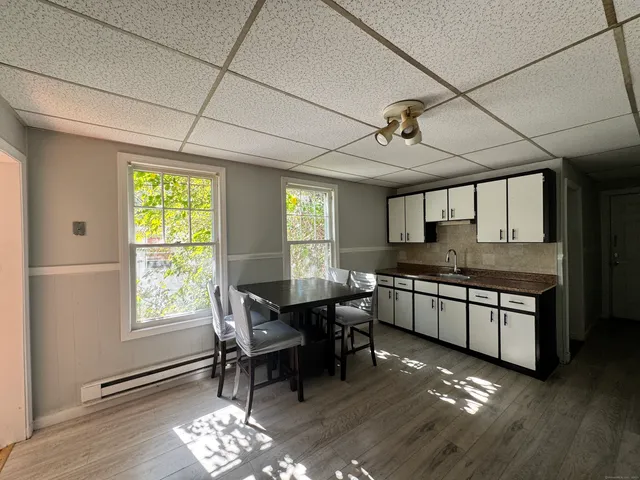 a kitchen with stainless steel appliances granite countertop a stove a sink dishwasher a dining table and chairs with wooden floor