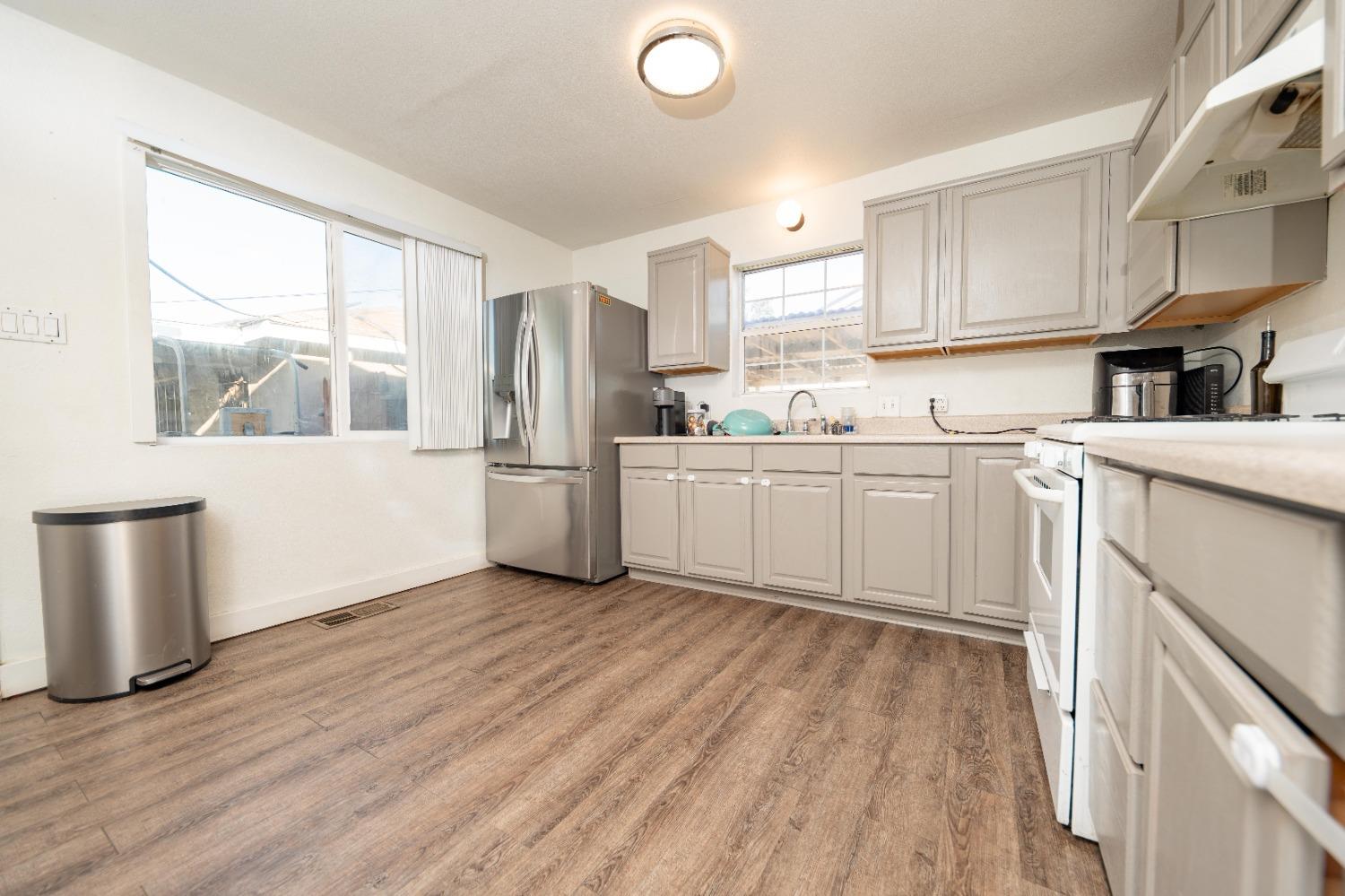 836 North E Street Tulare, CA 93274 - Photo 3 of 13 a kitchen with a sink a stove cabinets and wooden floor