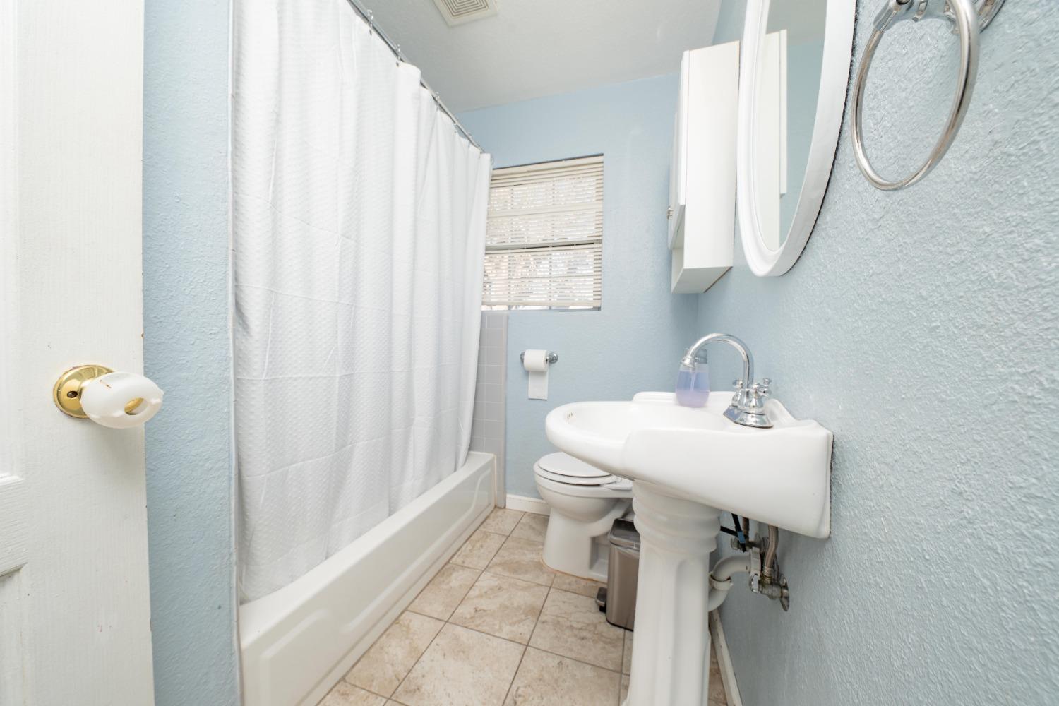 836 North E Street Tulare, CA 93274 - Photo 7 of 13 a bathroom with a sink toilet and a mirror