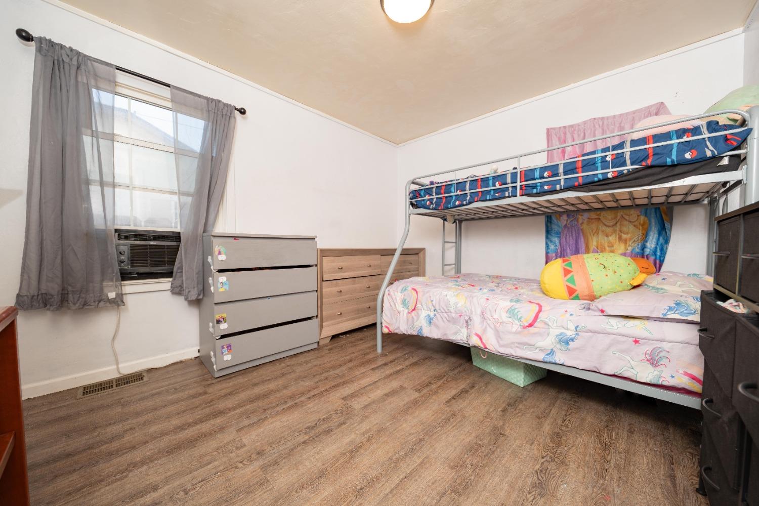 836 North E Street Tulare, CA 93274 - Photo 8 of 13 a bedroom with a bed and wooden floor