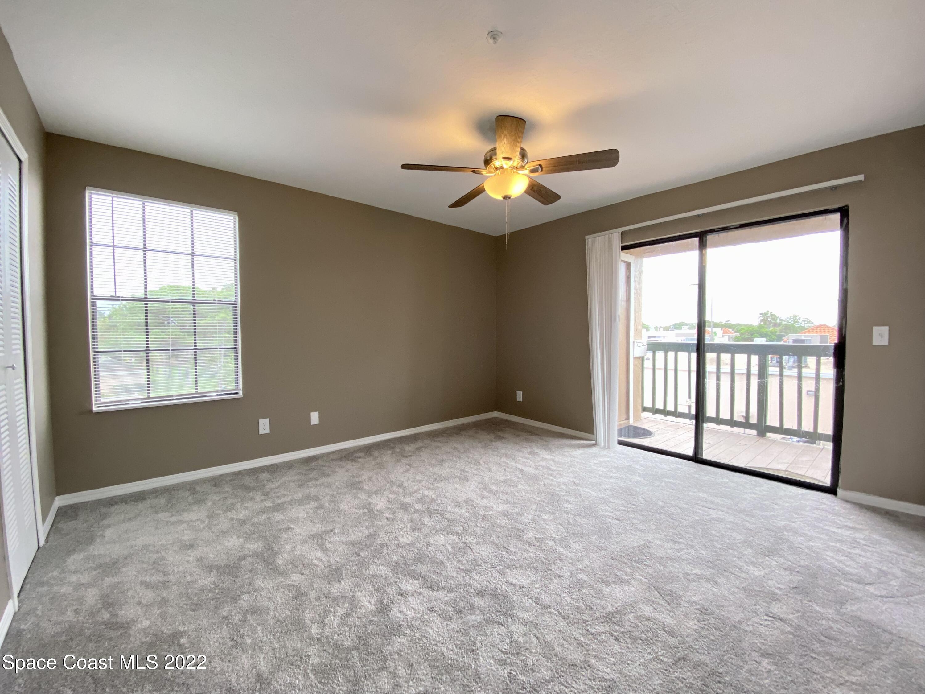 7667 North Wickham Road, Unit 418 Melbourne, FL 32940 - Photo 11 of 36 an empty room with chandelier fan and windows