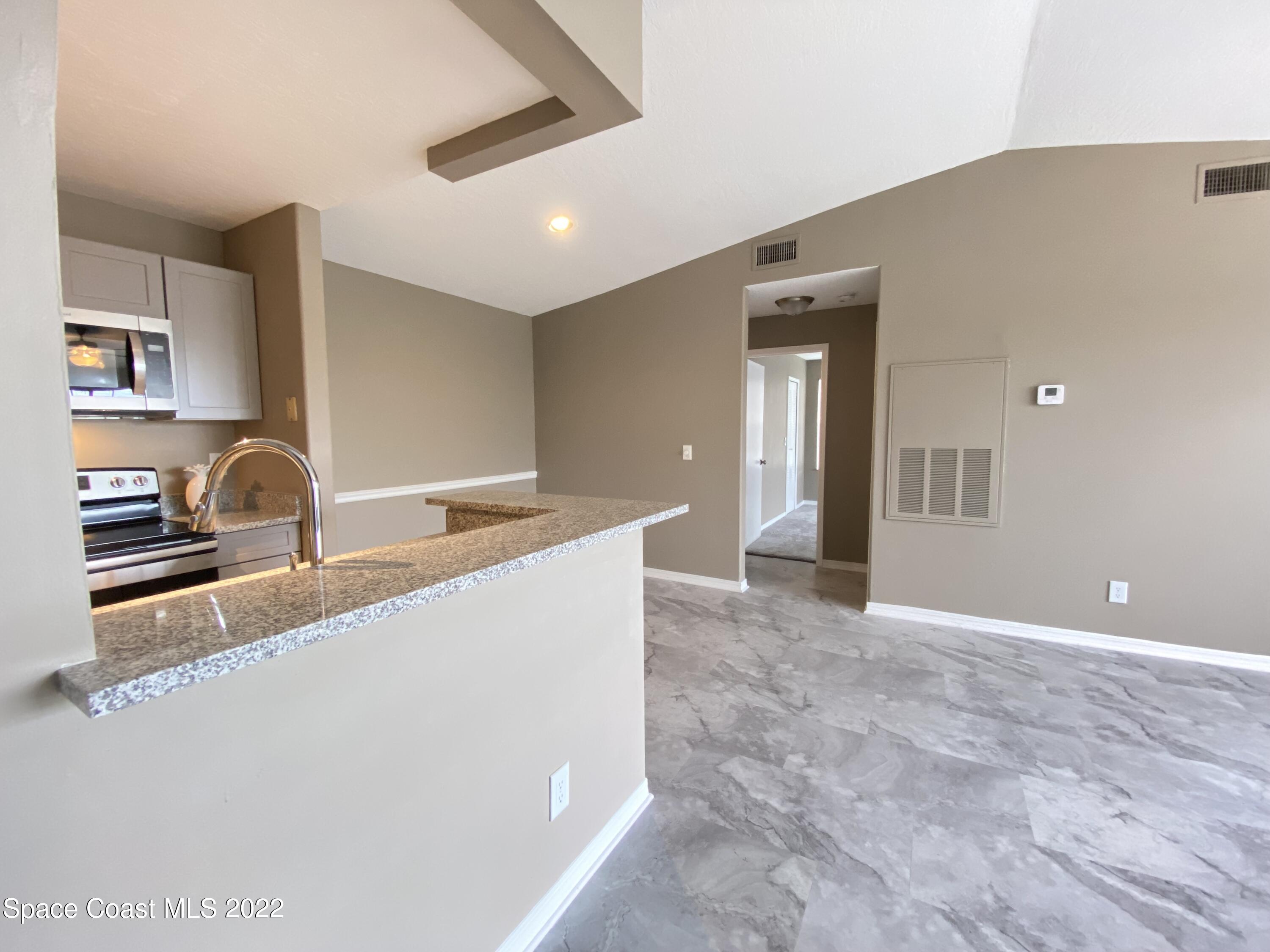 7667 North Wickham Road, Unit 418 Melbourne, FL 32940 - Photo 5 of 36 a view of a kitchen with a sink and a refrigerator